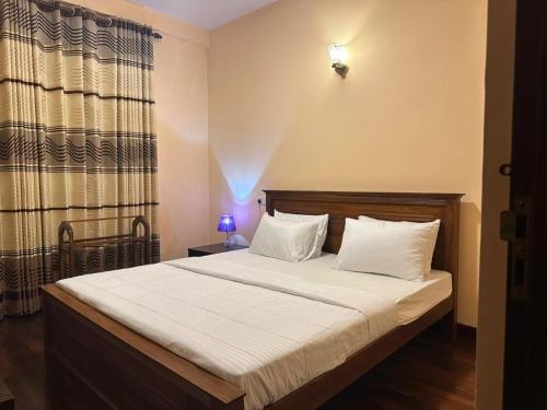 a bedroom with a bed with white sheets and pillows at Lake View By IJ in Nuwara Eliya