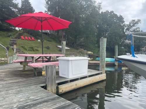 una mesa de picnic con una sombrilla roja en un muelle en Weems Creek Cottage, Annapolis Waterfront, en Annapolis