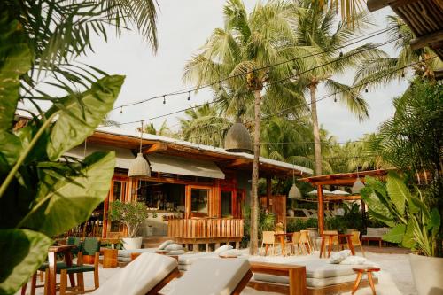a restaurant with tables and chairs and palm trees at Villas Caracol in Holbox Island