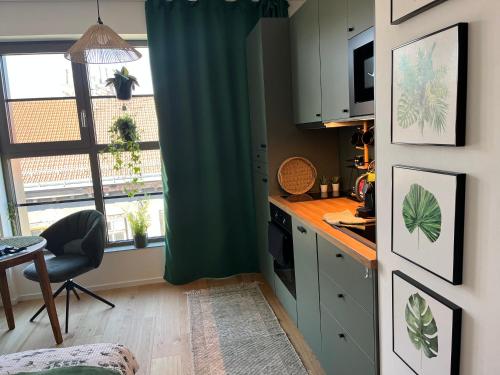 a kitchen with a green curtain and a table and a window at Jungle apartment in Brno