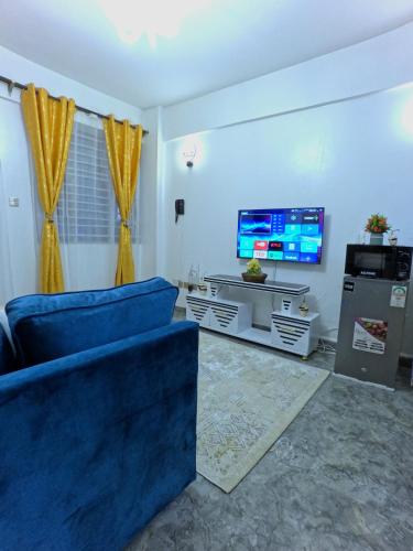 a living room with a blue couch and a tv at Jay Comfort home- Cozy 1BR next to Village Market, 2 Rivers mall, UN and The Embassies along Limuru Road in Ruaka