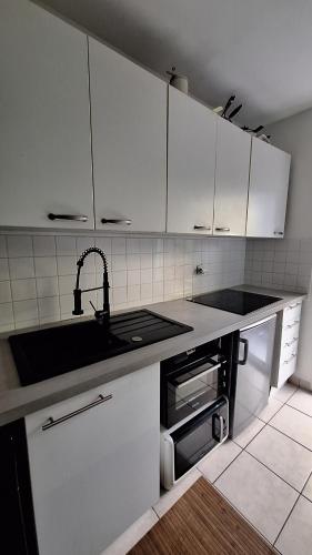 a kitchen with white cabinets and a sink at Bright T2 Workspace & WiFi Fiber, 5 min to Sophia Antipolis, 10 to Antibes in Mougins