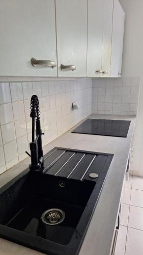 a kitchen with a black sink and white cabinets at Bright T2 Workspace & WiFi Fiber, 5 min to Sophia Antipolis, 10 to Antibes in Mougins