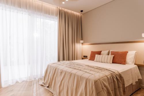 a bedroom with a large bed and a large window at Nuvélia, A Minimalist Luxury Story in Zakynthos Town