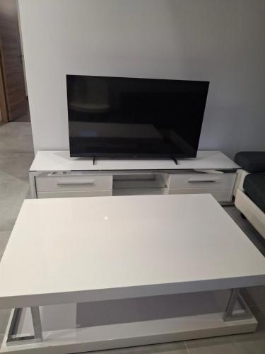 a white table with a flat screen tv on top at Appartement loft in Mandeure