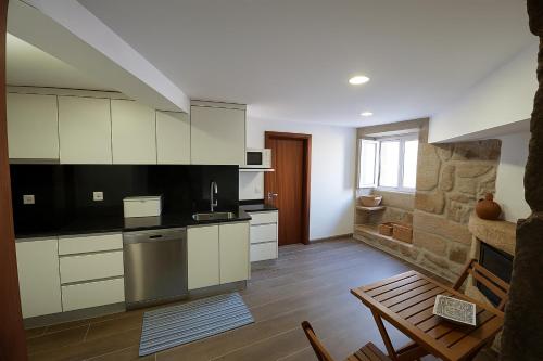 a kitchen with white cabinets and a wooden floor at Casa da Biquinha in Vouzela