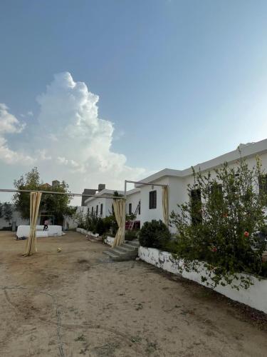 a white house with wooden poles in a yard at إستراحة البستان in Ash Shuwaybiţ