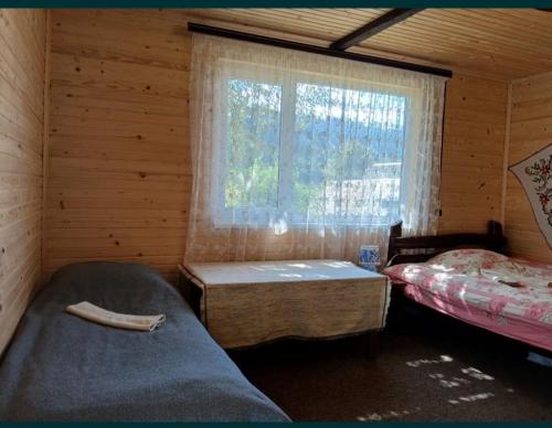 Habitación con 2 camas y ventana en una cabaña de madera. en Келечин 95, en Kelechin