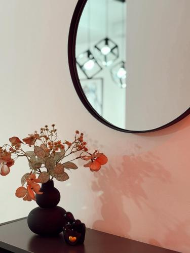 a black vase with flowers on a table in front of a mirror at Honey apartments in Ledine