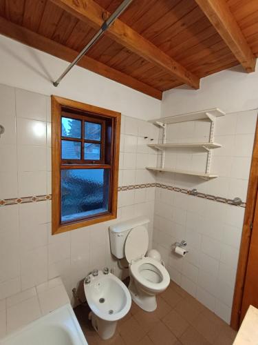 a bathroom with a toilet and a sink and a window at Casa Sueño in San Martín de los Andes