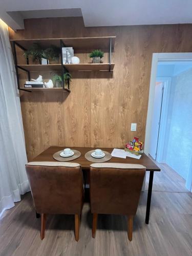 a dining room table with two chairs and a wooden wall at Studio aconchegante e tranquilo! Perto de tudo! in Indaial