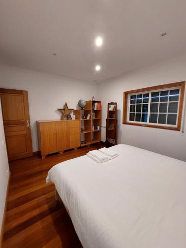 a bedroom with a large white bed and a window at Vivenda Juliano Freitas in Atães