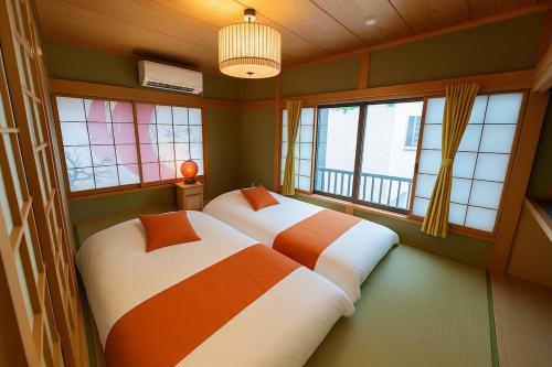 two beds in a room with two windows at Matsubara Station 2 minutes Shinjuku, Shibuya 15 minutes Pure Japanese style house where you can feel the seasons Maximum 6 people rent a house Quiet house in Tokyo