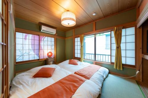 a bedroom with a large bed in a room with windows at Matsubara Station 2 minutes Shinjuku, Shibuya 15 minutes Pure Japanese style house where you can feel the seasons Maximum 6 people rent a house Quiet house in Tokyo