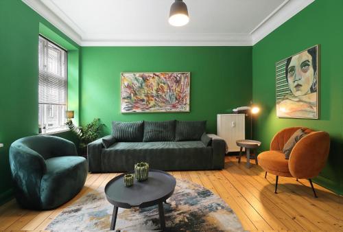 a living room with green walls and a couch and chairs at GreenBrook Homes in Aalborg