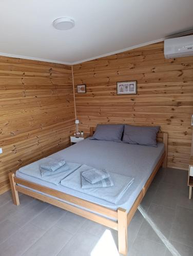 a bed in a room with a wooden wall at Vikendica Blagojević Čačak in Čačak