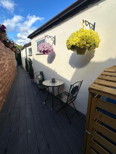 a patio with chairs and tables and flowers on a building at Roseleigh Cottage in the Heart of Cookham in Cookham