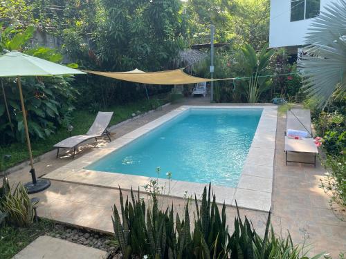 a swimming pool with a hammock in a garden at Wabi Sabi , casa de playa in Tamanique