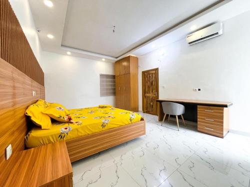 a bedroom with a yellow bed and a desk at Résidences Sica in Cotonou