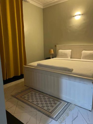 a bedroom with a large bed with yellow curtains at Fancy Bahai Residence- Kisaasi Bahai Road in Kampala