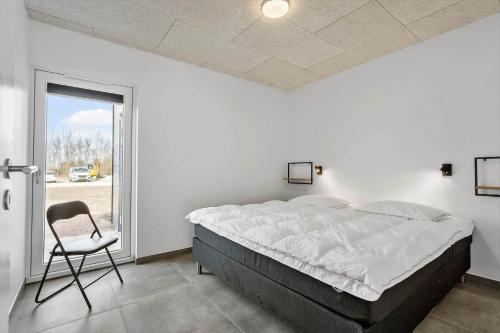 a bedroom with a large bed and a chair at 1125-Ringkobing-Dyrefolden-31 in Ringkøbing