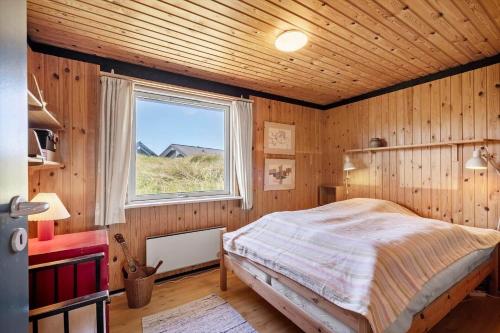 een slaapkamer met een bed in een kamer met een raam bij 1197-Ringkobing-Nordlysvej-17 in Søndervig