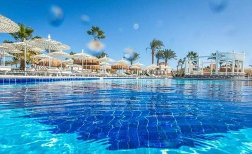 a large swimming pool with umbrellas and a resort at ميراج باي ريزورت أكوا بارك in Hurghada