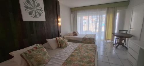a room with a bed and a table and a window at Búzios Beach Resort in Buzios