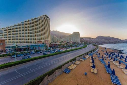 a beach with beach chairs and buildings and the ocean at Sky Sokhna -قمة التجربة الفاخرة مع بورتو رينتال in Ain Sokhna