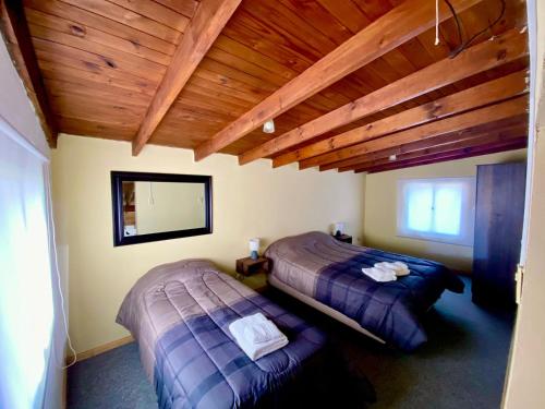 a bedroom with two beds and a wooden ceiling at Casa Los Huemules in El Chalten