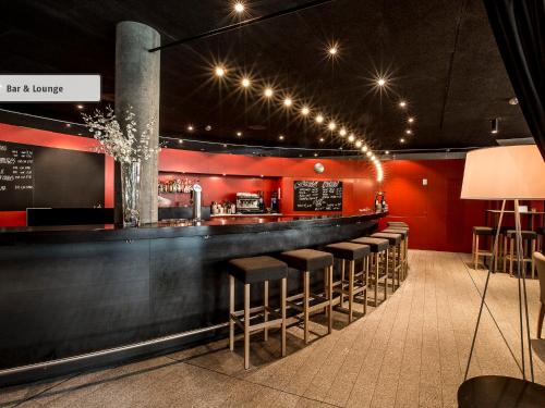 a bar with stools in a restaurant with red walls at All In One Hotel - Inn Lodge / Swiss Lodge in Celerina