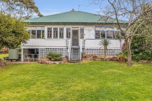 a white house with a green roof and a yard at East of Eden in Eden