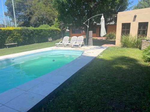 a swimming pool with two chairs and a umbrella at QUINTA LA ARAUCARIA -Paraná in Paraná
