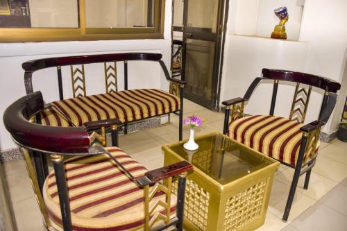 two chairs and a table with a vase in a room at Oscar Hotel Aswan in Aswan