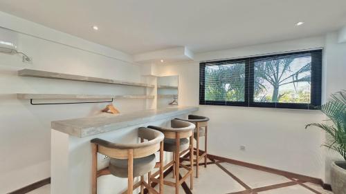 a kitchen with two bar stools and a counter at Canggu Villa - 7BR Private Cook, Pool, Rooftop Cinema in Canggu