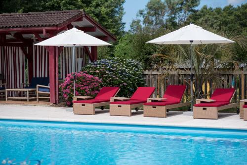 - un groupe de chaises longues et de parasols à côté de la piscine dans l'établissement Maison de Mézos, à Mézos
