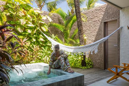 a man sitting in a hammock in a swimming pool at Saline Taíba Boutique Beach Hotel in Taíba