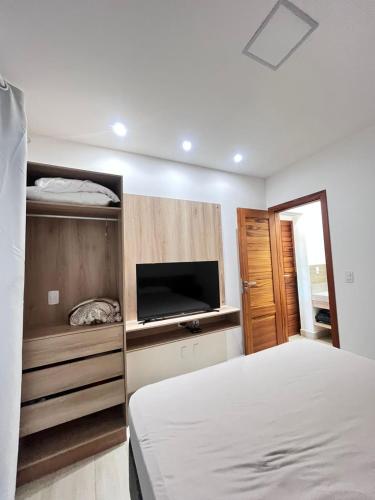 a bedroom with a bed and a flat screen tv at Flat Flecheiras in Trairi