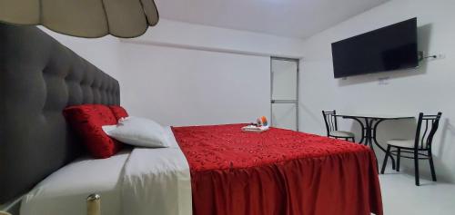 a bedroom with a bed with a red blanket and a table at Hospedaje El Paraiso in Santa Eulalia