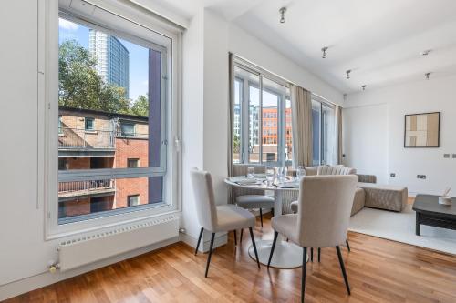 a dining room with a table and chairs and windows at Luxury Penthouse - Soho - Central - Sleeps 6 in London