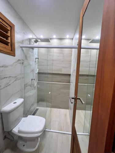 a bathroom with a toilet and a glass shower at Flat Flecheiras in Trairi