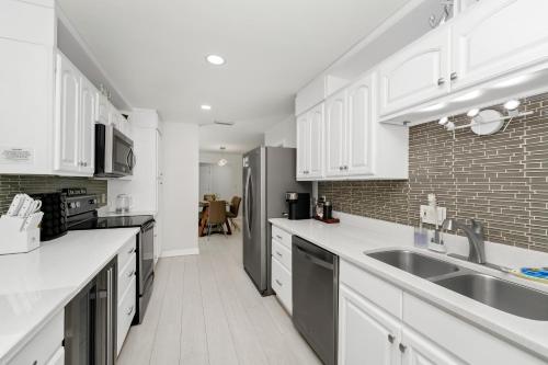 a kitchen with white cabinets and a brick wall at Lexy Beach House in Cape Canaveral