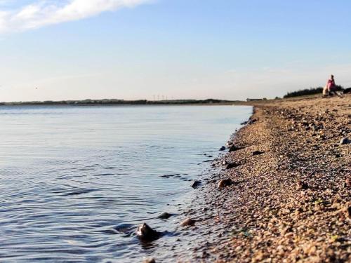 a person laying on the shore of a body of water at 6 person holiday home in Løgstør in Løgstør