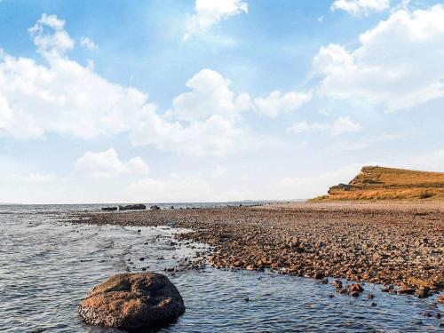a beach with a large rock in the water at 6 person holiday home in Farsø-By Traum in Farsø