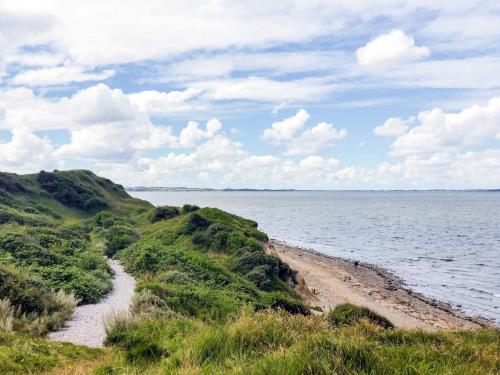 a beach with a body of water and clouds at 6 person holiday home in Farsø-By Traum in Farsø