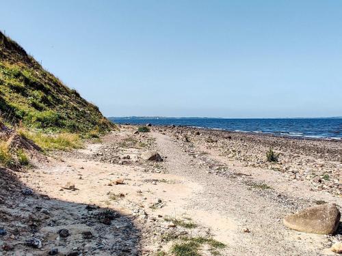 a dirt road next to the ocean on a beach at 6 person holiday home in Farsø-By Traum in Farsø