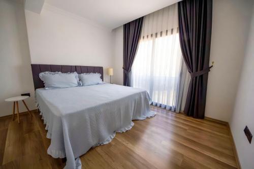 Cette chambre comprend un lit avec des draps blancs et une grande fenêtre. dans l'établissement Apartment Northern Cyprus, 