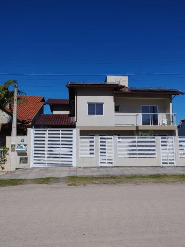 a white house with a red roof at Apartamento na Praia da Vila in Imbituba