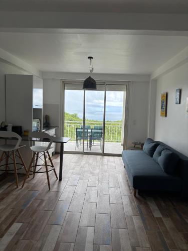 a living room with a blue couch and a table at EDEN-RÉSIDENCE Le TOBAGO Vue Mer et Piscine in Sainte-Luce