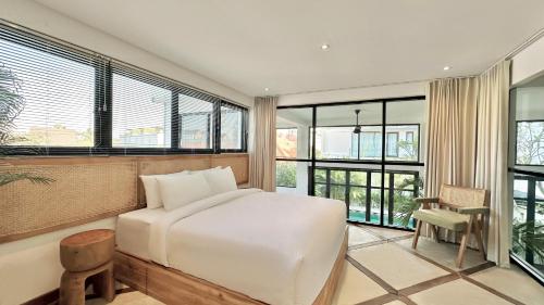 a bedroom with a white bed and some windows at Canggu Villa - 7BR Private Cook, Pool, Rooftop Cinema in Canggu